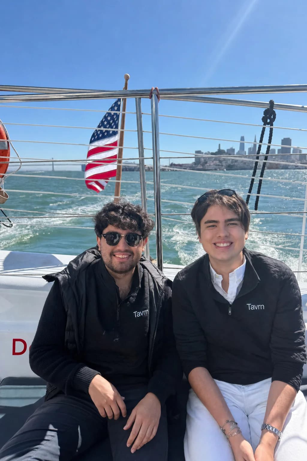 Pedro and Vitor, Tavrn’s founders, on the deck of a boat on San Francisco Bay with the city skyline behind them.